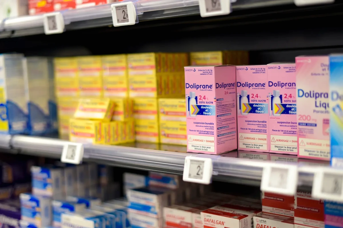 Boîtes de Doliprane enfants alignées sur une étagère de pharmacie, étiquettes et dosages visibles