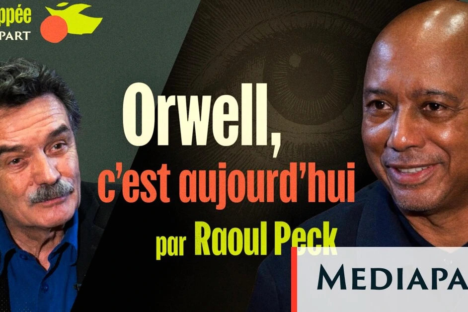 Raoul Peck en gros plan, assis lors d’une interview, regard tourné vers la caméra, fond sombre.