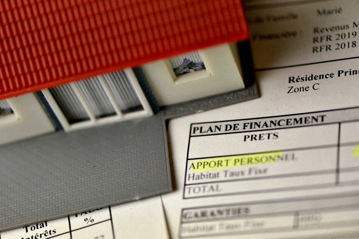 Un livret PEL ouvert sur un bureau, avec une notification « fermeture automatique » affichée sur un smartphone