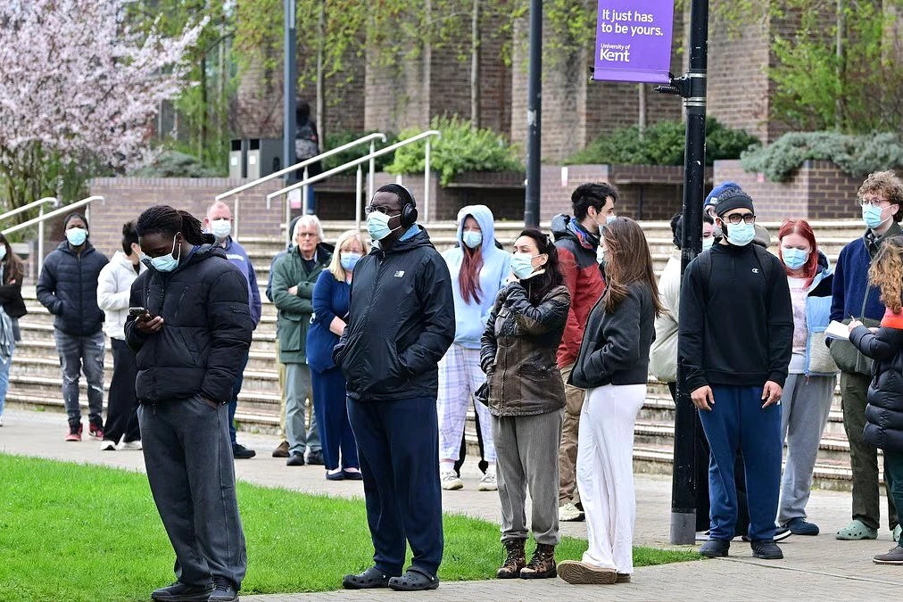 Agent du Kent en gilet fluorescent devant une ambulance et l’entrée d’un hôpital, enquête sur des cas de méningite