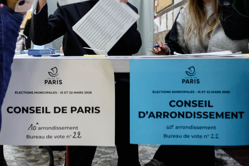 Bulletins de vote et urne transparente, avec carte de Paris et mention des candidats au 2nd tour par arrondissement