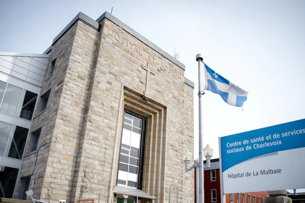Chantier de l’hôpital de La Malbaie avec engins de construction et panneaux de travaux à l’entrée