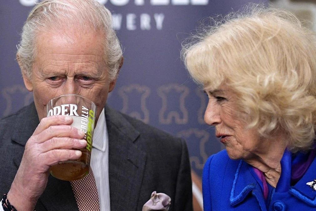 Charles III saluant la foule devant un bâtiment officiel aux États-Unis, drapeaux américains en arrière-plan