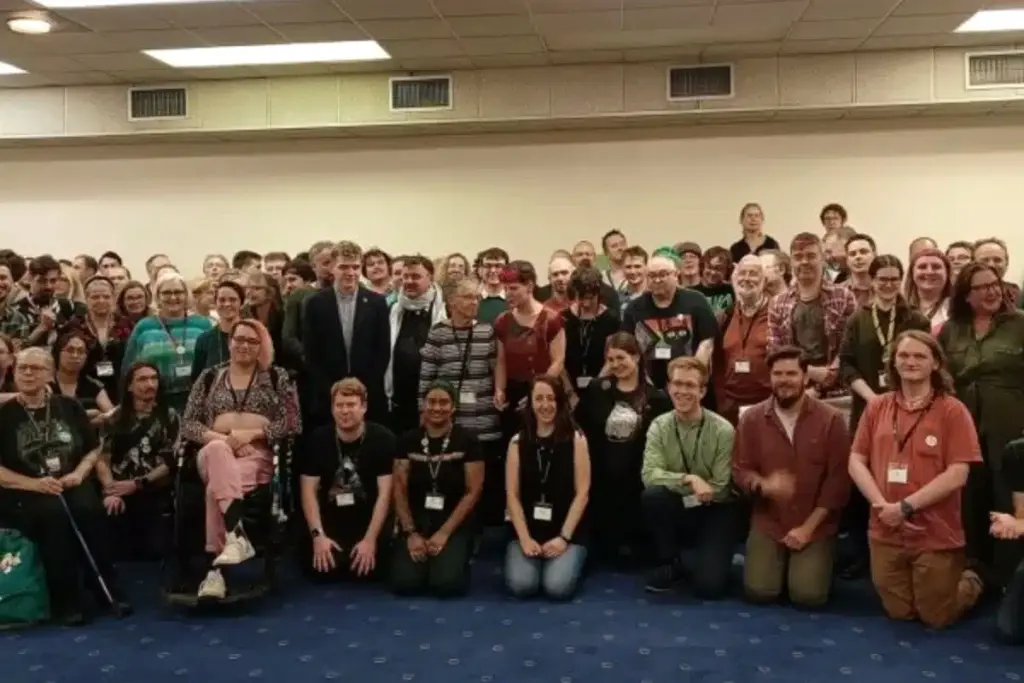 Cheffe du Parti vert au pupitre, devant des députés, avec le titre « Motion de censure » en arrière-plan