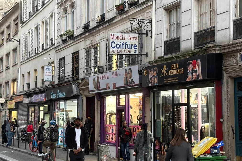 Coiffeur afro à Château-d’Eau à Paris, devant un salon fermé au couvre-feu, rideau métallique baissé