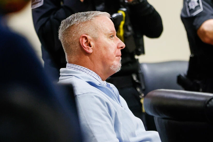 Colin Gray menotté escorté par des policiers devant Apalachee High School, véhicules de patrouille en arrière-plan