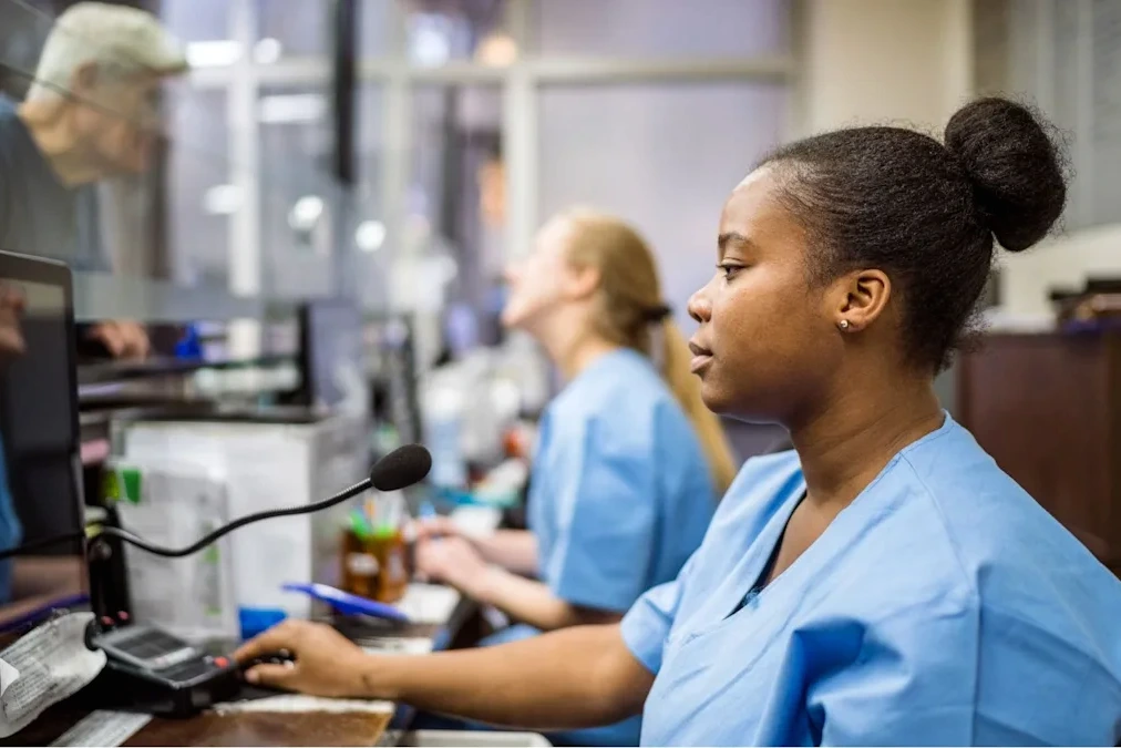 Couloir d’hôpital au pays de Galles, patients assis en salle d’attente et panneau d’accueil visible