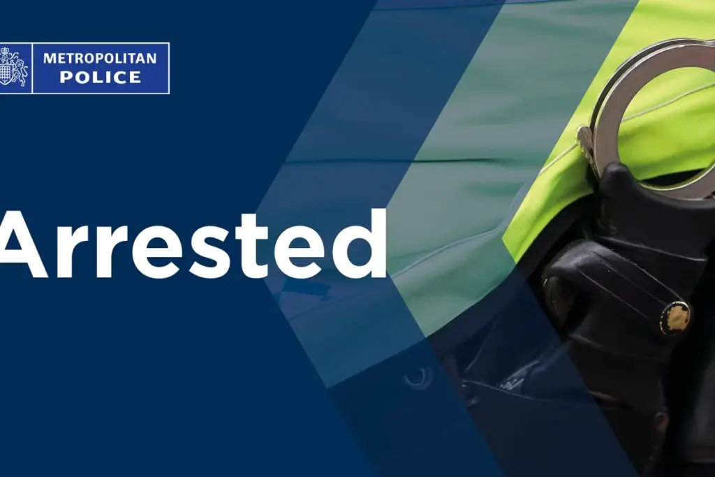 Deux hommes menottés escortés par la police devant des ambulances juives incendiées, gyrophares allumés