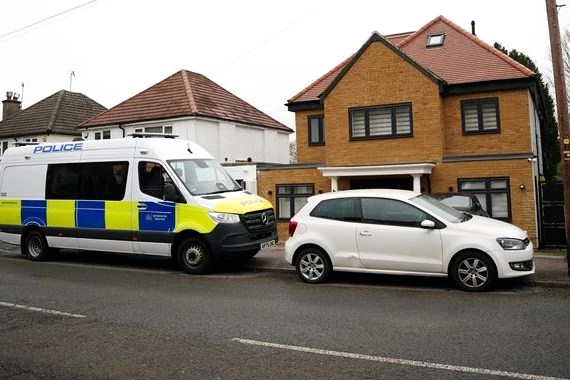 Deux hommes menottés escortés par la police devant un bâtiment à Londres, liés à l’espionnage présumé pour l’Iran