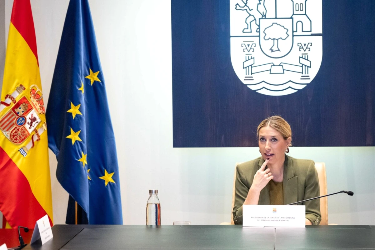 Dirigeants du PP et de Vox se serrant la main devant des drapeaux, lors d’une réunion en Estrémadure