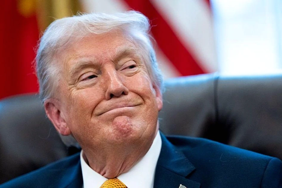 Donald Trump au pupitre lors d’un meeting, micro devant lui, drapeaux américains en arrière-plan