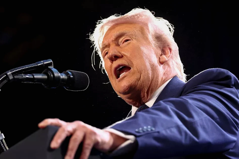 Donald Trump s’exprime devant des drapeaux américains, micro au pupitre, lors d’une conférence de presse.