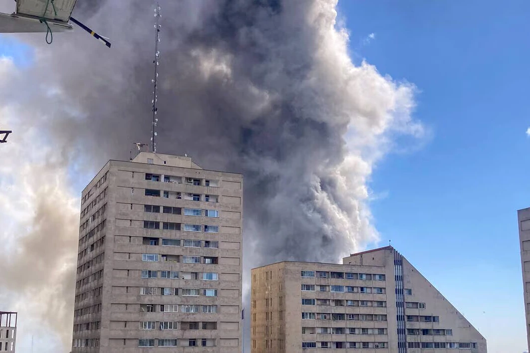 Drapeau des Gardiens de la Révolution iranienne flottant devant un bâtiment, avec soldats en uniforme au premier plan