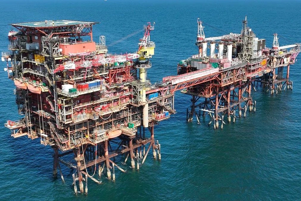 Drapeau du Royaume-Uni devant des réservoirs de gaz et un pipeline, jauges presque vides en arrière-plan