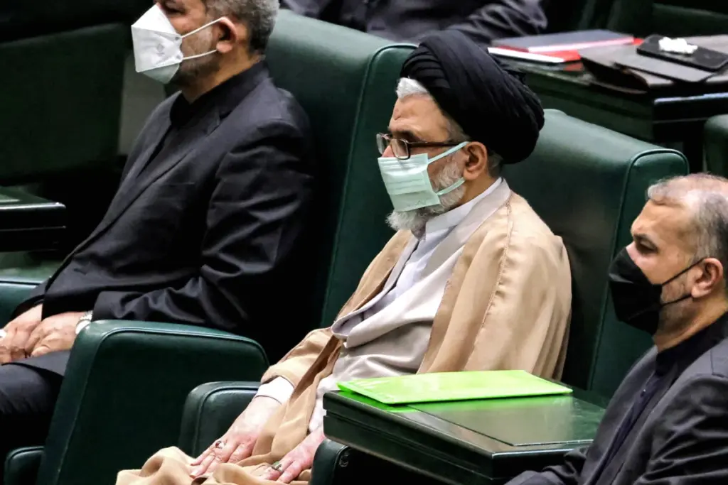 Drapeaux d’Israël et de l’Iran face à face, avec silhouette d’un ministre iranien du Renseignement en arrière-plan