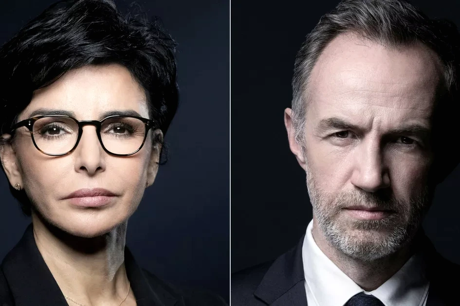 Emmanuel Grégoire en gros plan lors d’un meeting à Paris, micro en main, devant des drapeaux et une foule