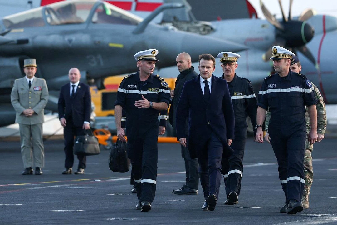 Emmanuel Macron en costume s’exprime au pupitre lors d’une conférence de presse, drapeaux français en arrière-plan