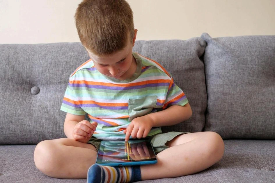 Enfant de moins de 5 ans regardant une tablette, avec une horloge indiquant 1 heure de temps d’écran par jour