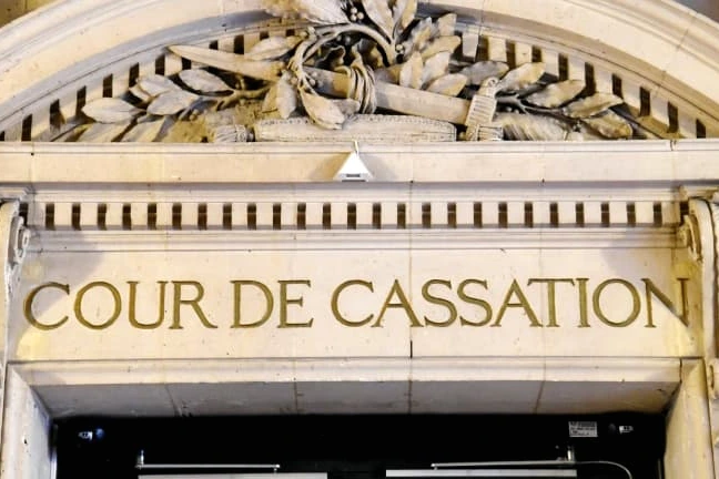Façade de la Cour de cassation à Paris, avec colonnes et drapeau français au premier plan