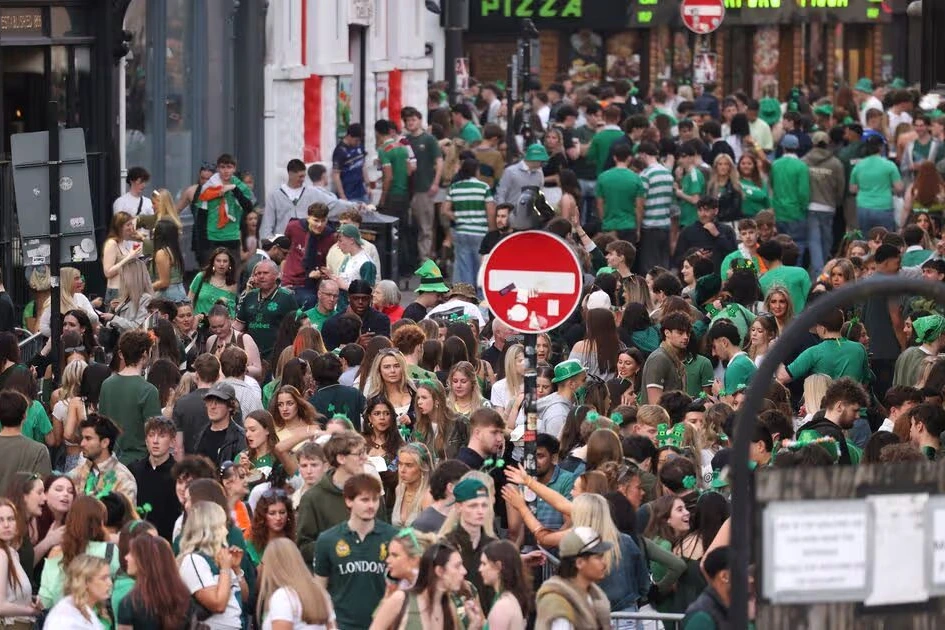 Foule dense à Liverpool bloquant une rue du centre-ville, drapeaux verts et tenues de la Saint-Patrick