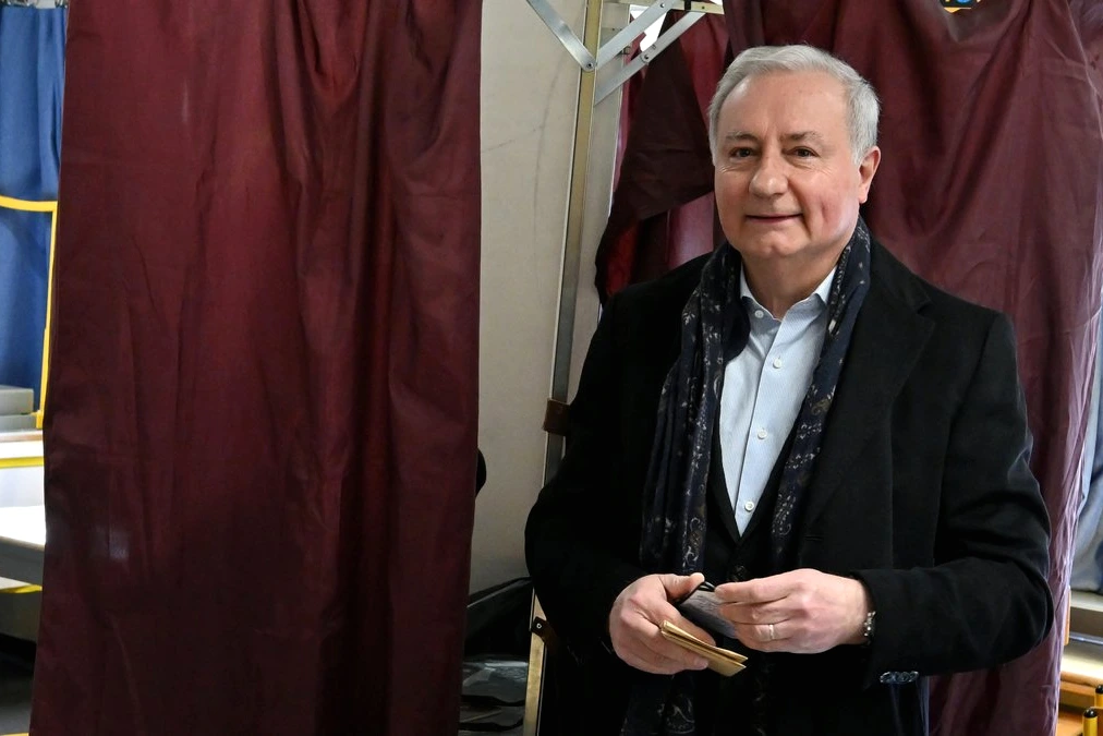 Jean-Luc Moudenc au micro devant une foule à Toulouse, avec banderole et drapeaux en arrière-plan