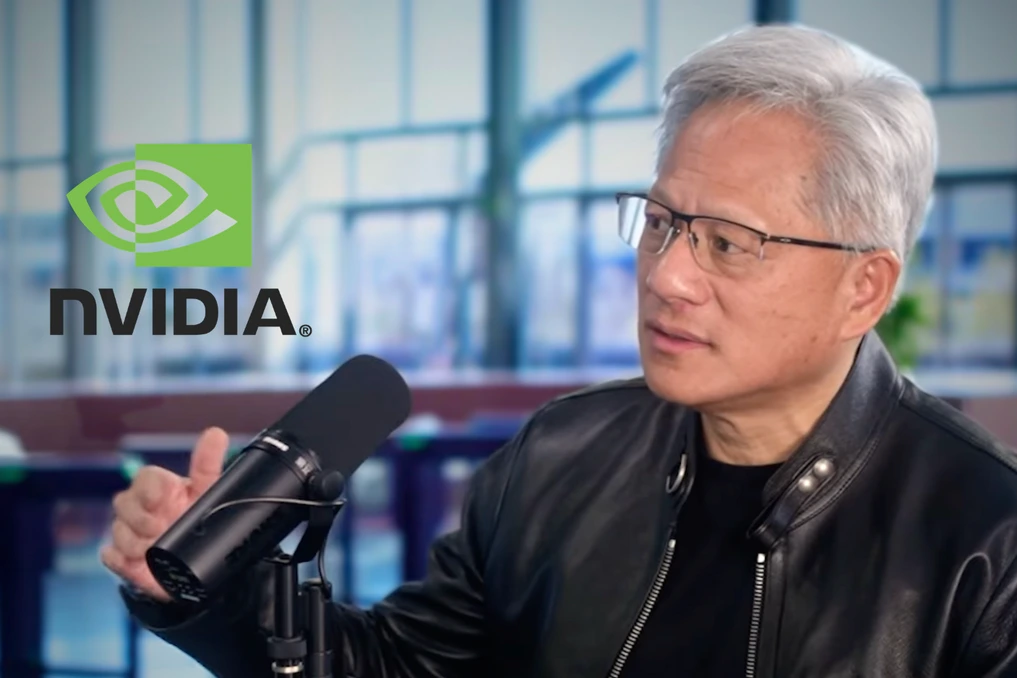 Jensen Huang sur scène lors d’une conférence, parlant au micro devant un écran géant en arrière-plan