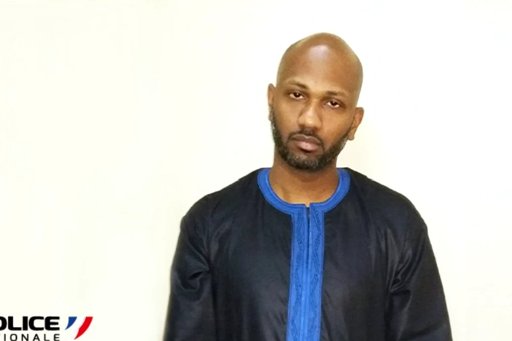 Joël Soudron menotté, encadré par des policiers panaméens, devant un véhicule de police au Panama