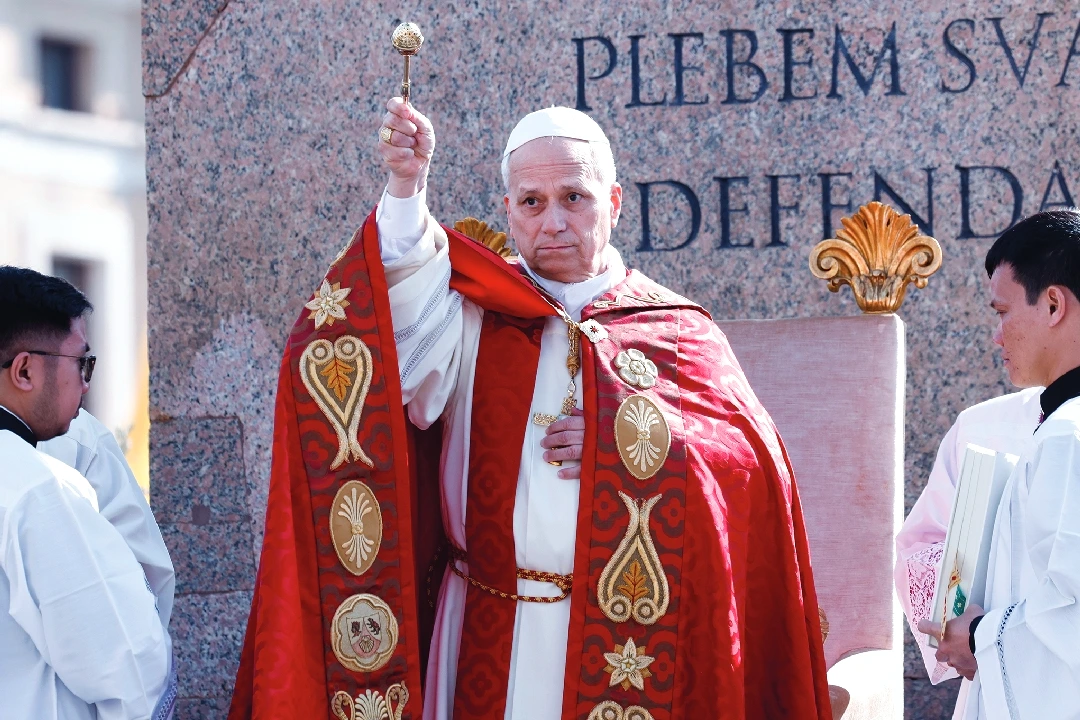 Le pape Léon XIV en tenue blanche salue la foule depuis un balcon du Vatican, main levée