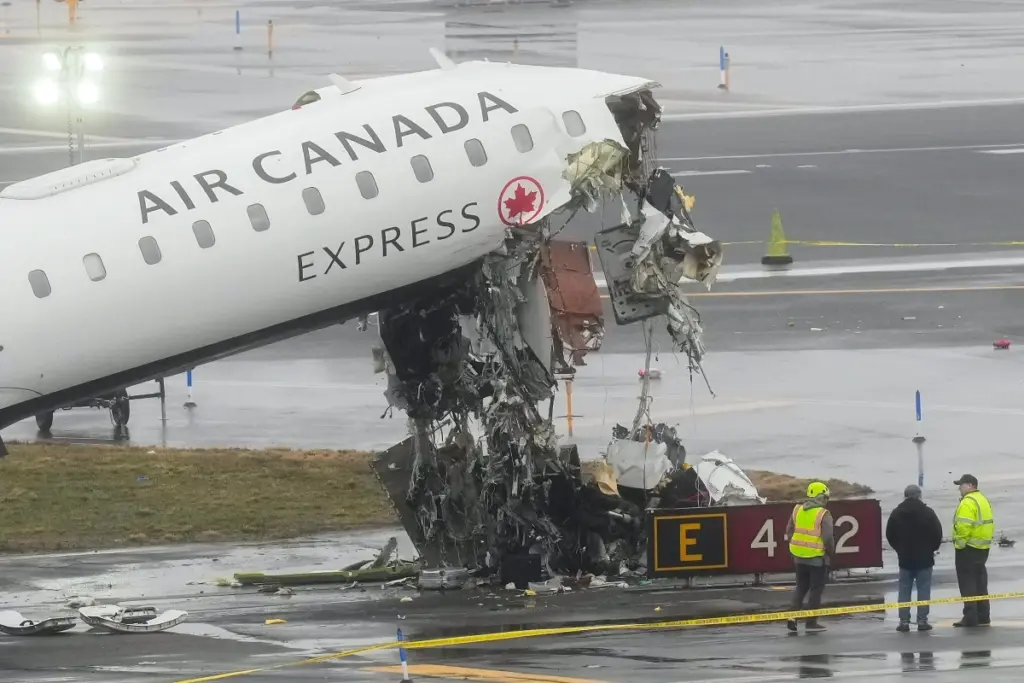 Le PDG d’Air Canada en costume, devant un avion Air Canada sur le tarmac, salue des employés.