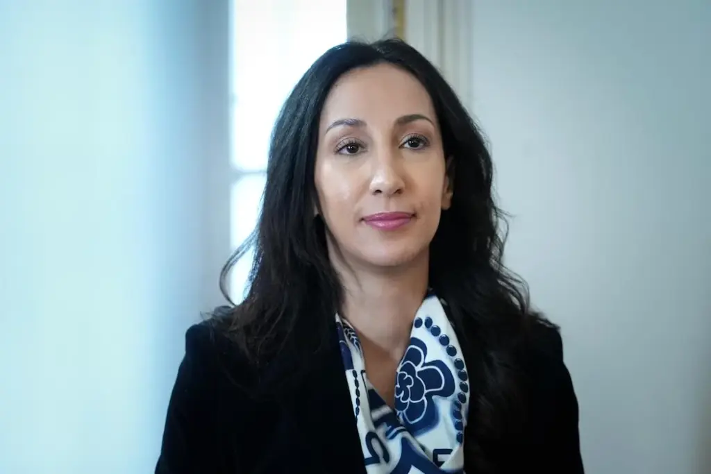 Marwah Rizqy en gros plan, regard sérieux, devant un fond neutre, éclairage doux sur son visage.