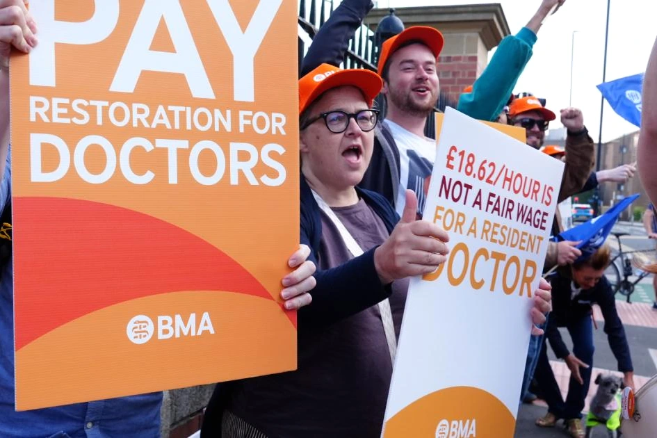 Médecins résidents en Angleterre en grève, pancartes et blouses blanches devant un hôpital