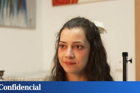 Noelia, 25 ans, assise sur un lit d’hôpital, regardant par la fenêtre, lumière douce en arrière-plan