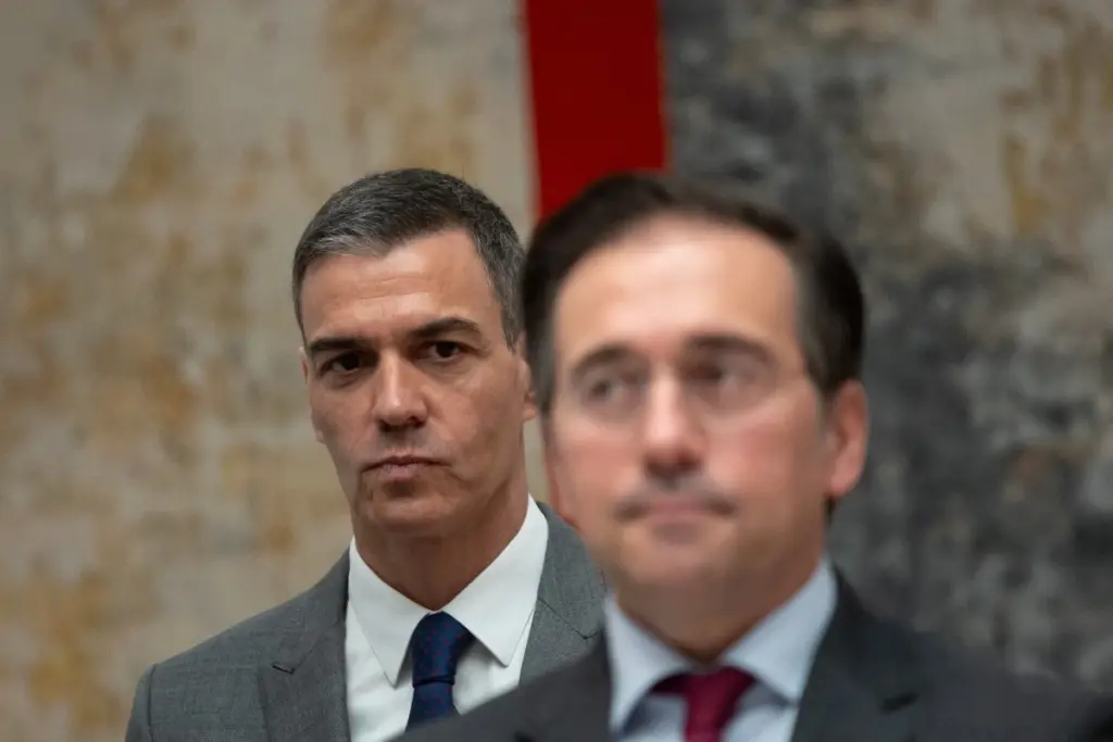 Passagers espagnols avec valises attendent en file à l’aéroport du golfe Persique, sous panneaux d’embarquement.