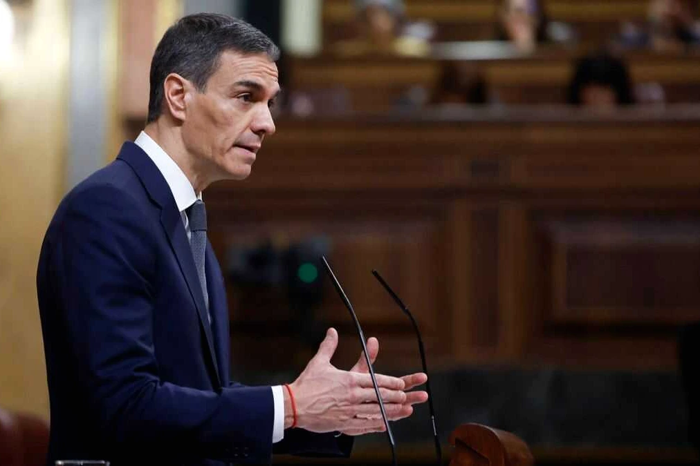 Pedro Sánchez s’exprime au pupitre devant le Congrès, drapeaux espagnols en arrière-plan.