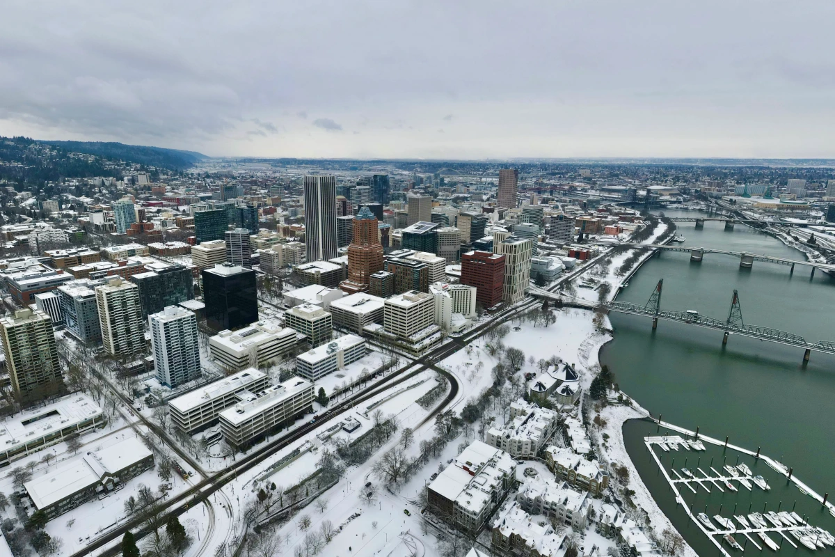 Portland sous un ciel gris, rues mouillées et flocons de neige possibles au-dessus des bâtiments en arrière-plan