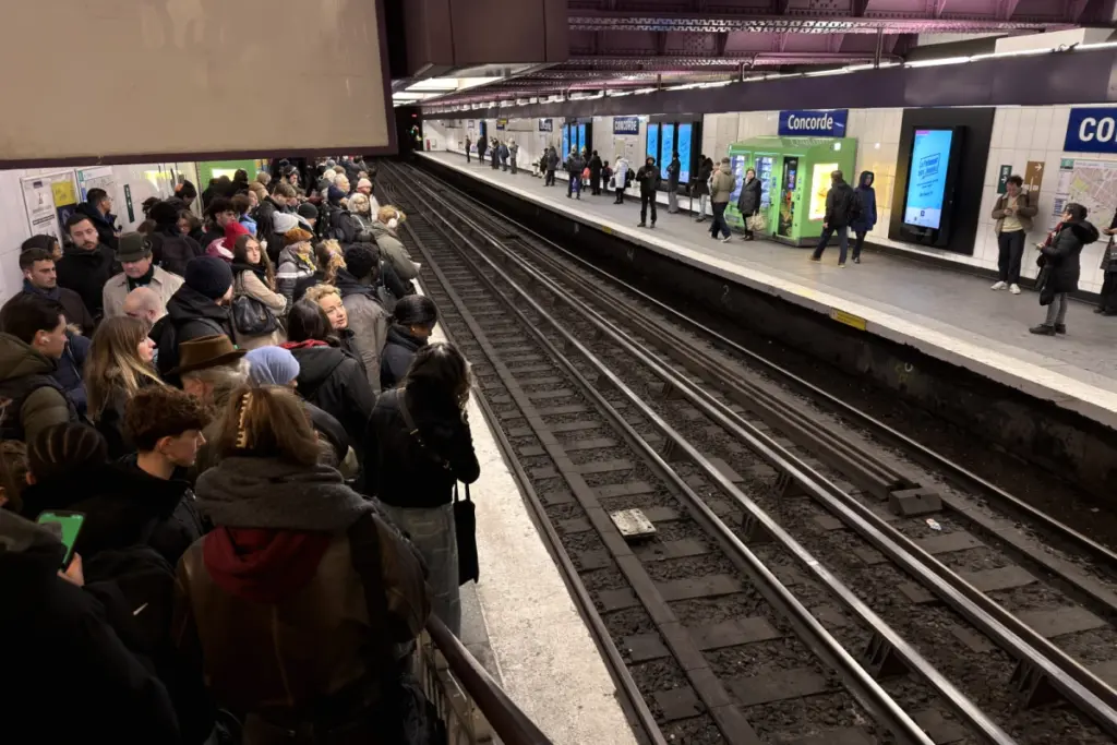 Rame de RER à quai dans une station parisienne, voyageurs sur le quai, panneau d’information perturbations
