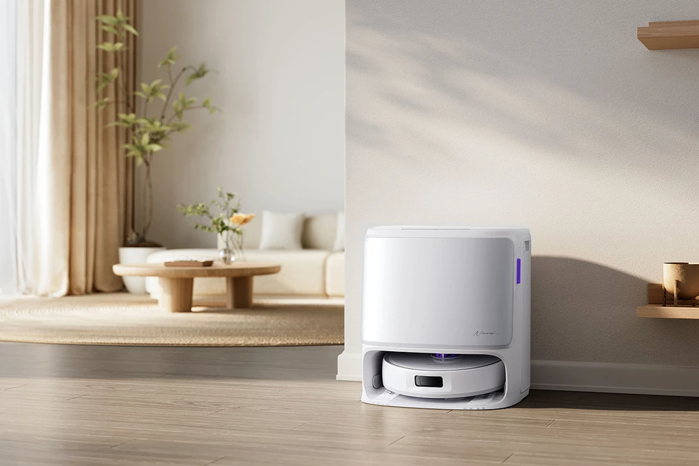 Robot aspirateur Narwal Freo Z10 Pro blanc, vu en gros plan sur sol clair, avec station de charge en arrière-plan