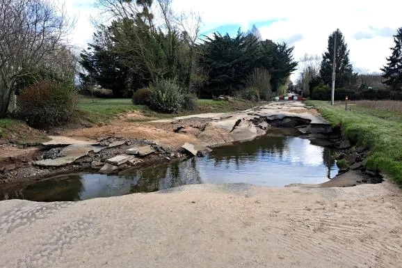 Route effondrée dans une commune du Maine-et-Loire, large fissure et barrières de sécurité visibles