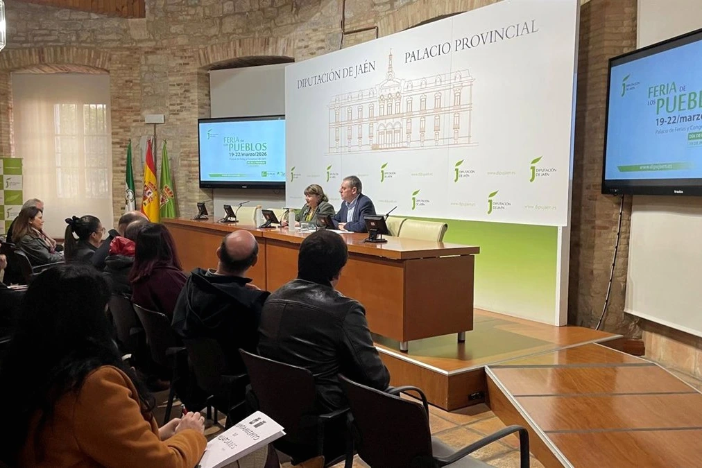 Stands colorés et visiteurs à La Feria de los Pueblos, avec animations et drapeaux en plein air.