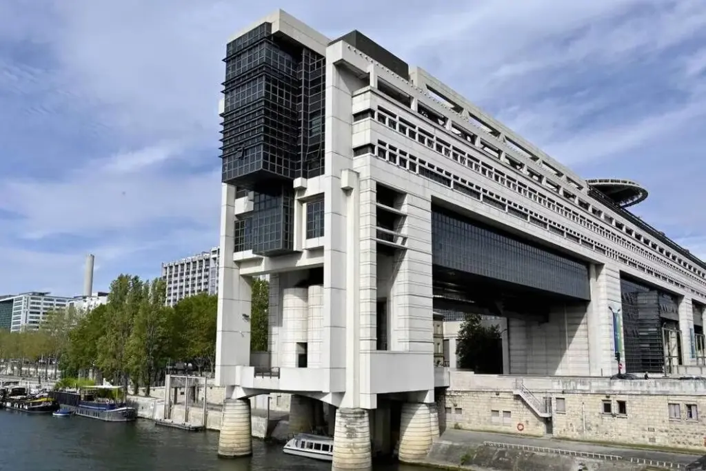 Station-service avec panneaux de prix du carburant, un agent du ministère de l’Économie en contrôle.