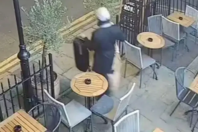 Technicien vérifiant un appareil avec un smartphone et un ordinateur portable sur un bureau, écran allumé