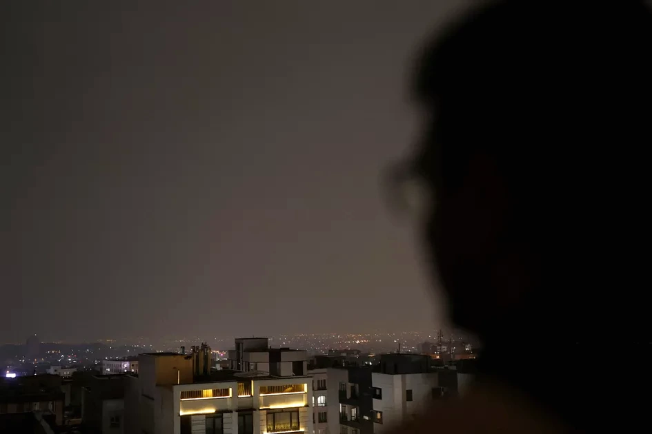 Techniciens inspectant des lignes électriques endommagées en Iran, avec pylônes et câbles sous un ciel gris