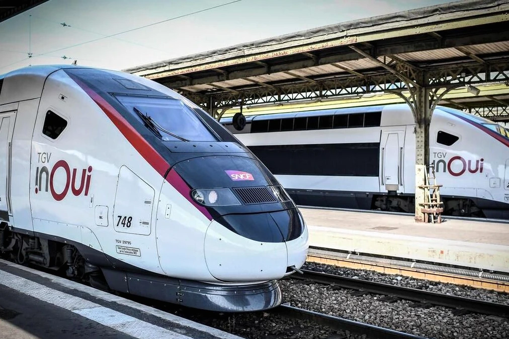 TGV Marseille-Paris à l’arrêt en gare, voyageurs sur le quai près des panneaux d’information, retard affiché