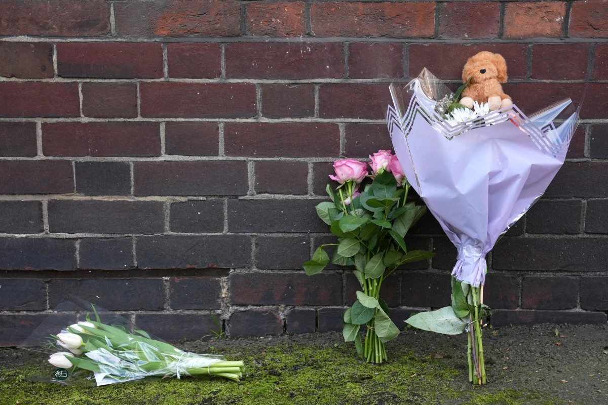 Une mère menottée escortée par la police, tandis qu’un bébé est transporté sur une civière en arrière-plan.