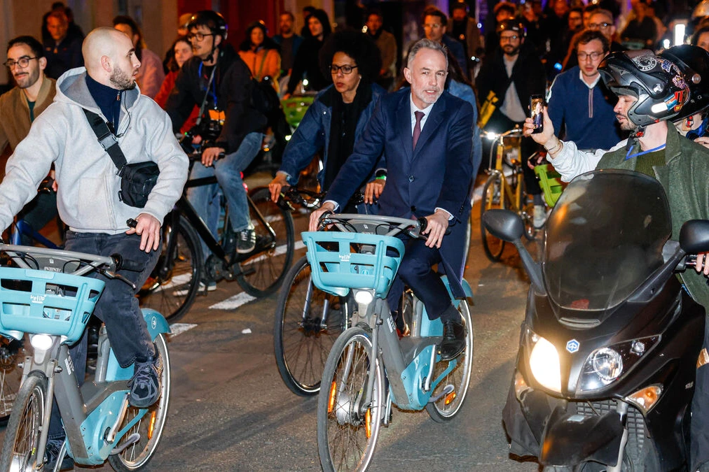 Vélib’ du maire à Paris stationné près d’une borne, avec des passants et des immeubles en arrière-plan