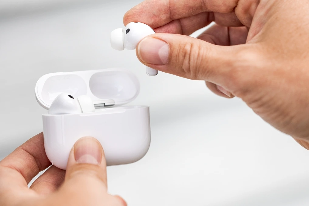 AirPods posés près d’un smartphone Android affichant le Play Store et une application de gestion AirPods