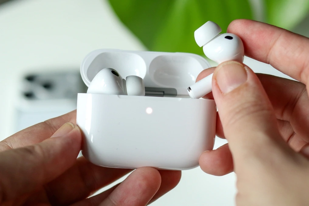 AirPods Pro 2026 blancs posés dans leur boîtier ouvert, gros plan sur les écouteurs et la tige