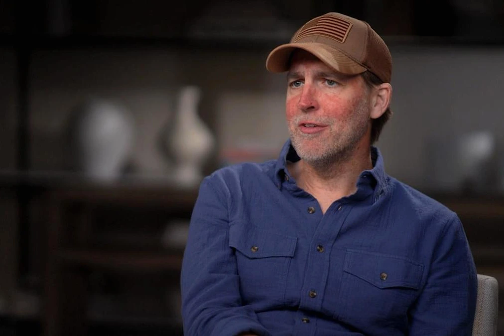 Ben Sasse en costume, portrait en gros plan, regard sérieux, devant un fond neutre et flou.