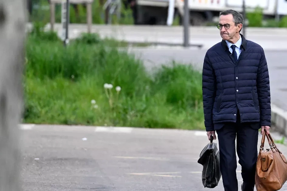 Bruno Retailleau en costume, en extérieur, marchant sur une route bordée d’obstacles et de panneaux vers 2027