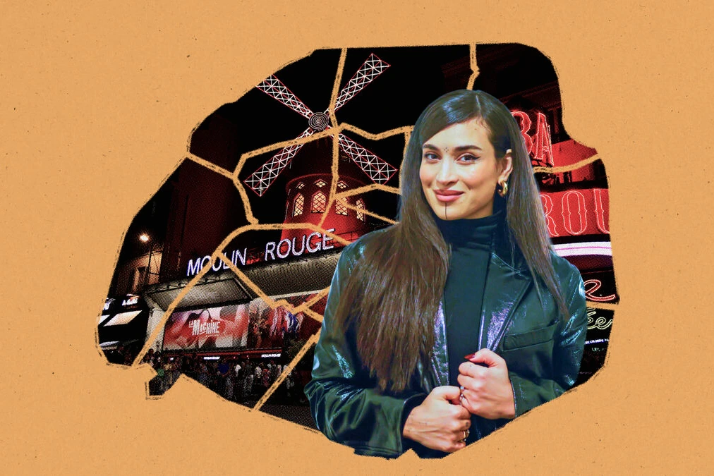 Camélia Jordana posant dans une rue parisienne, avec des immeubles haussmanniens en arrière-plan.